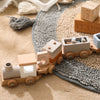 A wooden train toy featuring glass beads and numbered blocks, resting on a textured fabric surface.