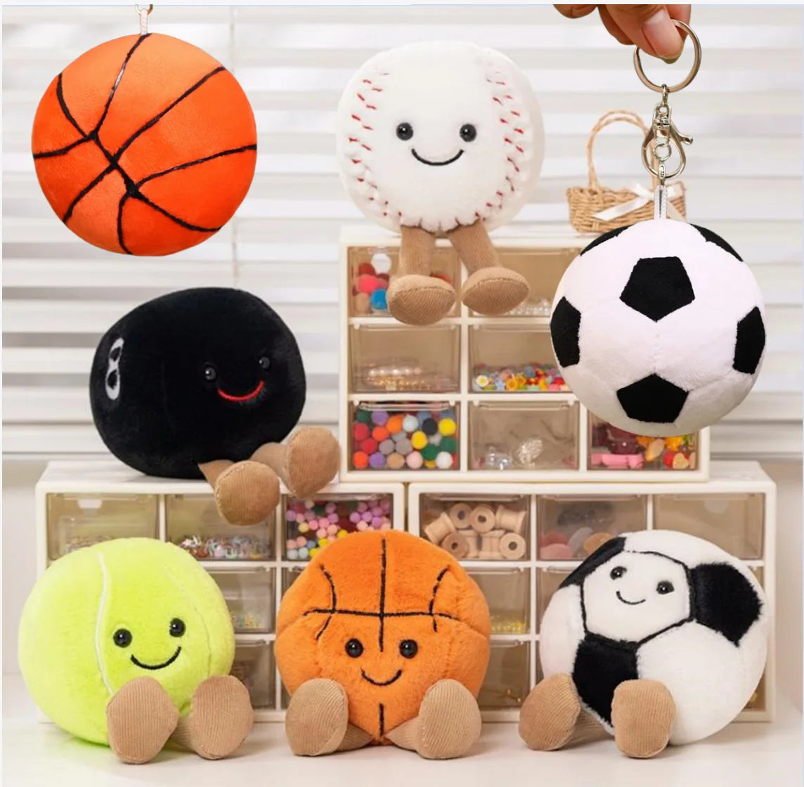 A collection of cute sports themed plush dolls including an orange basketball, a black soccer ball, a yellow tennis ball, and