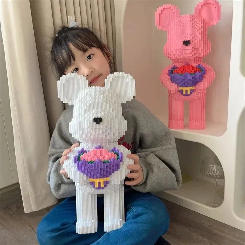 A young girl holds a white bear building block set with pink and purple flower accents in front of a light pink shelf.
