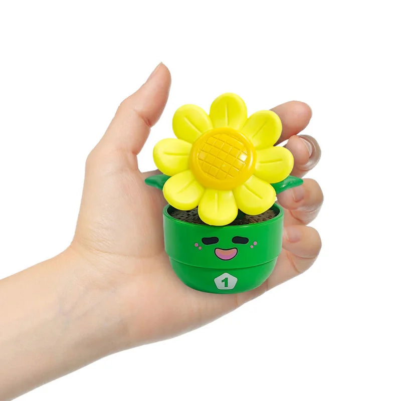 A hand holds a bright yellow flower toy with a green pot and a small number 1 on the bottom.