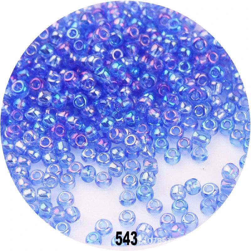 A close-up view of small, round, loose blue and purple glass seed beads for jewelry making.