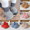 A collection of cozy suede baby booties in various colors including pink, red, blue, and beige with plush fur lining.