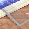A stainless steel cross ruler used for diamond painting is shown resting on a wooden surface.