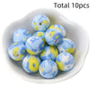 A collection of ten blue silicone beads with yellow floral patterns in a white dish.