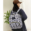 A woman wearing a striped shirt holds a black and white cartoon print waterproof diaper bag.