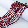 Strands of reddish-purple faceted glass crystal beads draped across a white surface.