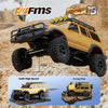 A yellow 1:18 scale remote control off-road climbing jeep with a front bumper and auxiliary lights on rocky terrain.
