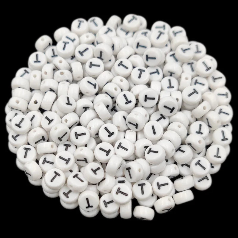 A pile of small white acrylic alphabet letter beads for jewelry making