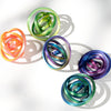 A collection of colorful, spiraled rings or spinners in various shades of green, orange, and purple, casting shadows on a whi