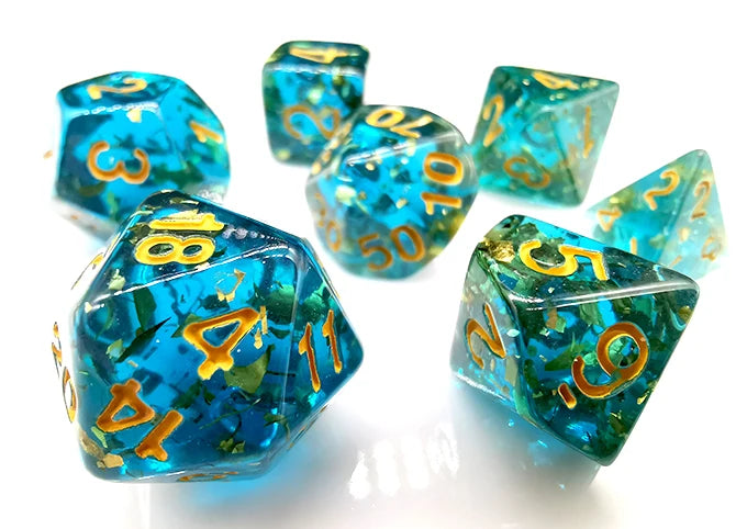 A collection of ocean blue resin dice with gold foil numbers scattered on a white surface.
