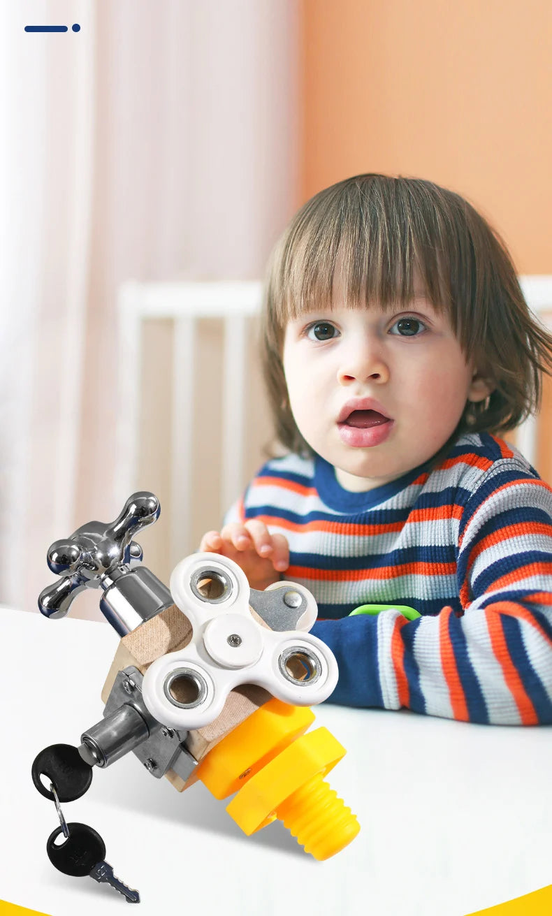 A child is looking at a wooden busy cube toy with brass fittings and a yellow piece on a white table.