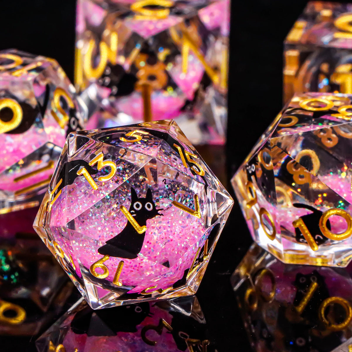 A close-up of a set of pink and gold liquid core dice, shaped like pyramids, reflecting on a dark surface.
