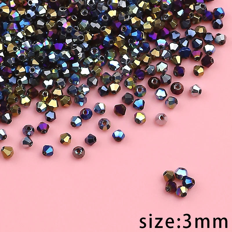A pile of small, faceted crystal glass beads in various shades of purple, blue, and gold on a pink background.
