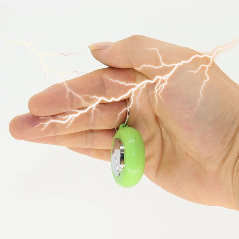 A hand is holding a green electric shock buzzer toy, with visible lightning bolts surrounding the hand.