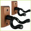 A set of dark wood guitar wall mounts with black curved hangers for securing musical instruments.