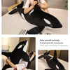 A woman is cuddling a black and white lifelike orca whale plush toy on a bed.