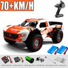 Orange and white high-speed 4WD brushless RC monster truck with a remote control visible.