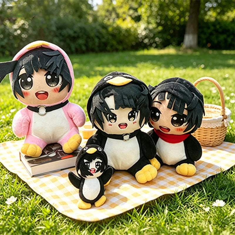 A collection of black and white penguin plush toys with pink accents sitting on a checkered mat in a grassy outdoor setting.