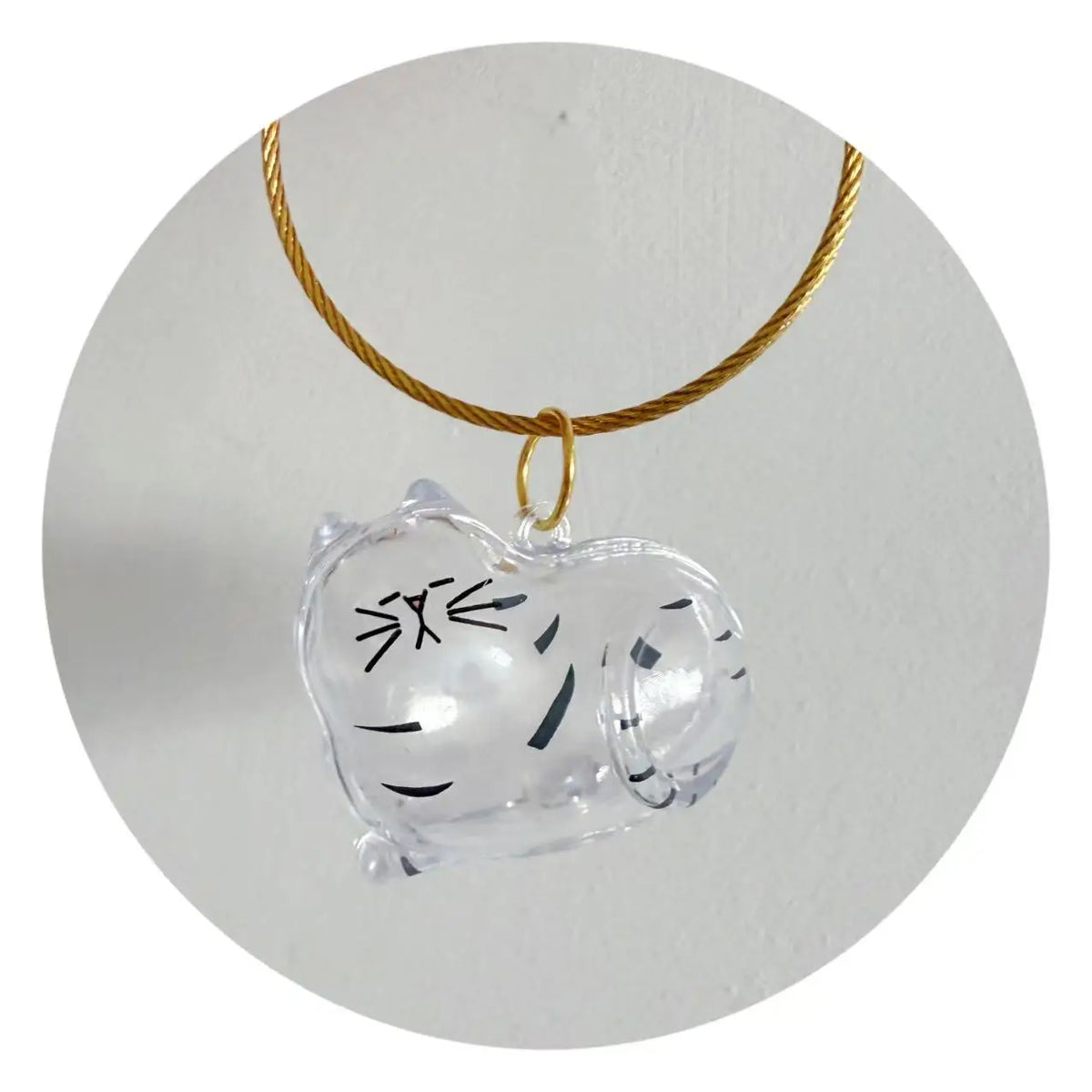 A clear, dog-shaped keepsake charm attached to a gold-colored chain.
