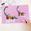 A hand is using a pink tool to attach a geometric dinosaur sticker to a sheet of paper.