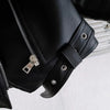 Close-up of a black faux leather zip-up jacket sleeve showing stitching and hardware.