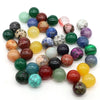 A collection of polished crystal spheres in various shades of green, pink, yellow, and purple.