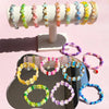 A display of various colored frosted golden foil acrylic beads on a white stand.