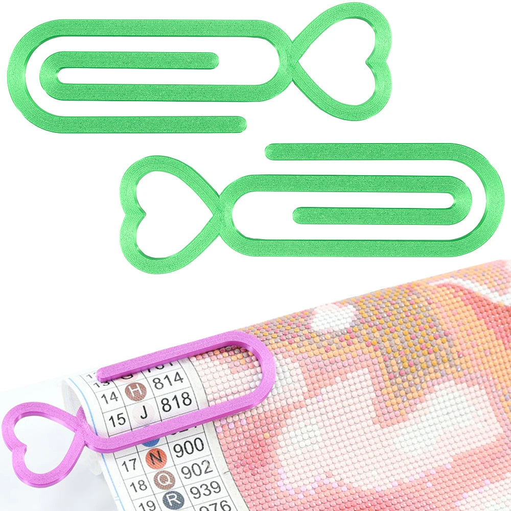 A set of two green plastic clips shaped like hearts and oval loops for holding diamond painting canvas.