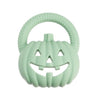 A light green silicone pumpkin baby teether with a textured handle and carved face features.