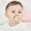 A baby wearing a personalized pacifier with a crown design and storage case.
