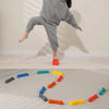 Rainbow sensory stepping stones in various colors arranged in a curved path on a light-colored floor.