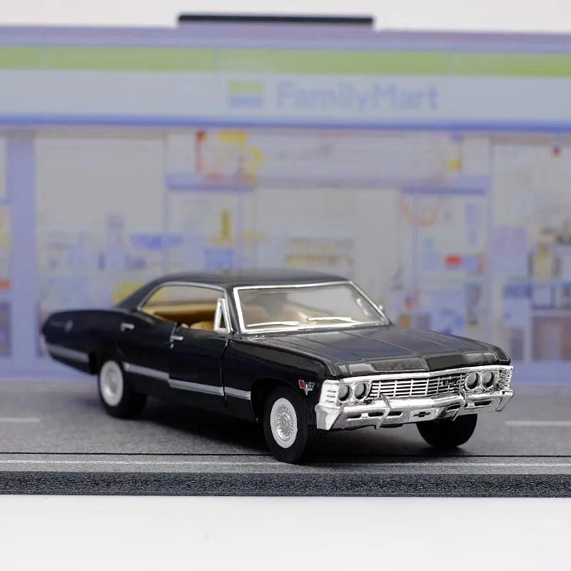 A black 1967 Chevrolet Impala diecast model car with a chrome grille and brightwork, displayed on a gray surface.