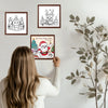 A person is looking at a framed coloring page featuring Santa Claus and Christmas trees.