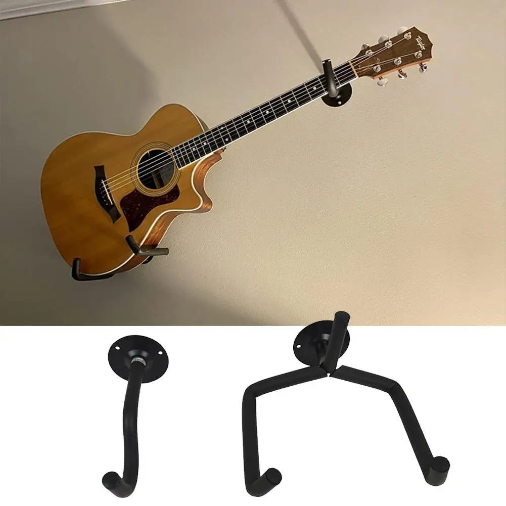 A wooden acoustic guitar is hanging on a black metal wall mount hanger.