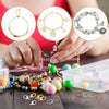 Hands are assembling jewelry using lobster clasps and open jump rings for crafting.