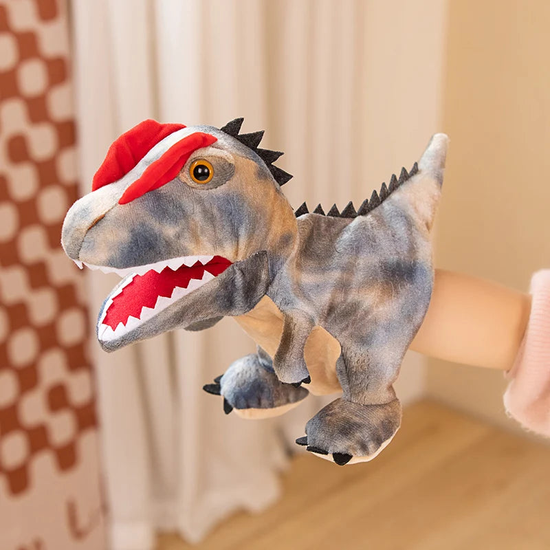 Marionnette en peluche d'un dinosaure gris avec des accents rouges, sur fond clair.