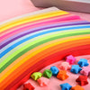 Colorful origami star strips in a rainbow gradient are laid out on pink paper for crafting