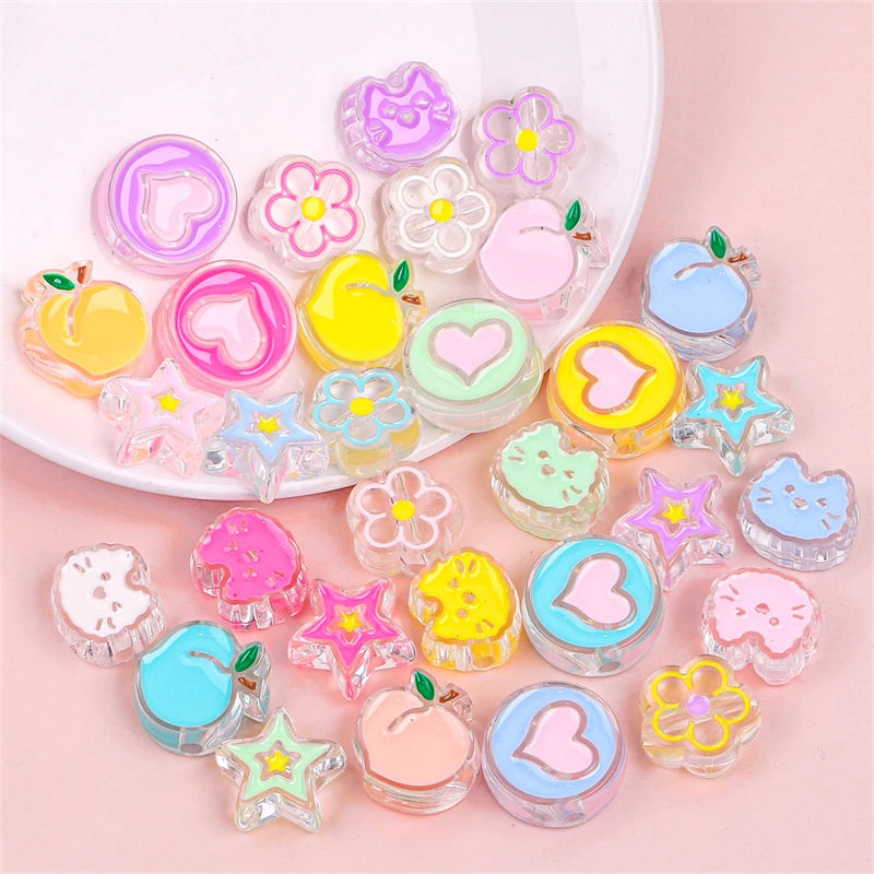 A collection of colorful enamel charm beads in various shapes and colors arranged on a pink surface.