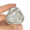 A hand holds a silver metal magnetic fidget slider with concentric grooves and small spheres.