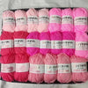 A pack of pink and coral colored acrylic yarn skeins for knitting and crochet crafts.