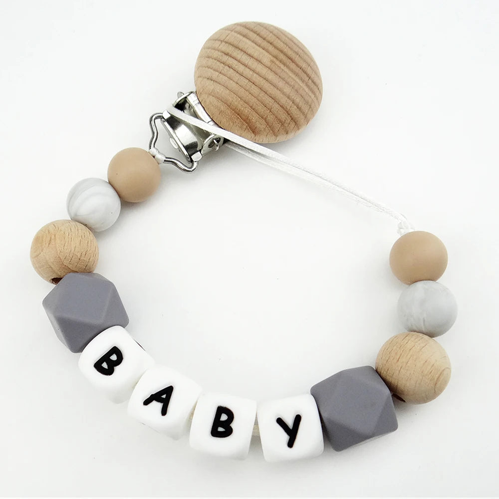 A personalized pacifier clip featuring wooden and silicone teething beads in various neutral tones.