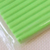 A close-up of a bright lime green polymer clay block with ribbed texture resting on a white surface.