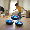 A young boy is playing with glowing LED hover soccer balls on a wooden floor.