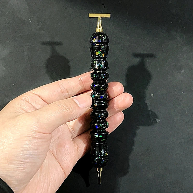 A hand holds a colorful diamond painting pen with a stainless steel tip, displaying its intricate design.