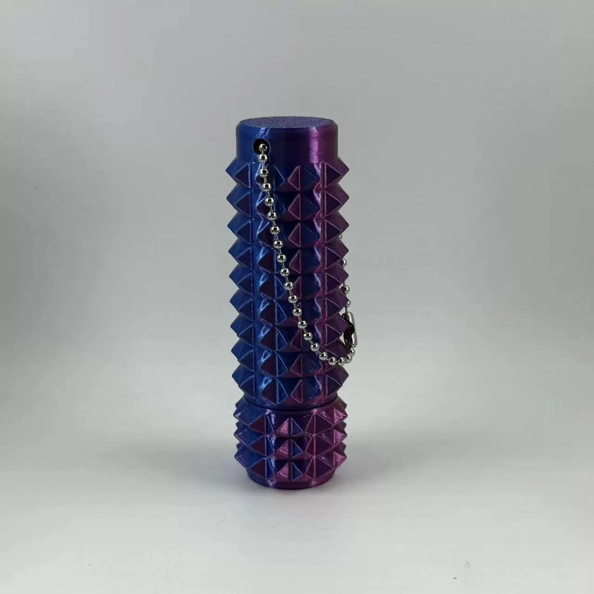 A stack of purple and blue spike roller fidget toys with silver chain keychains.