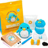 A crochet kit for beginners featuring a penguin toy and yarn, including a needle and a finished knitted item.