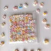 A clear plastic bag filled with numerous small, colorful floral-shaped squishy stress relief fidget toys scattered on a white