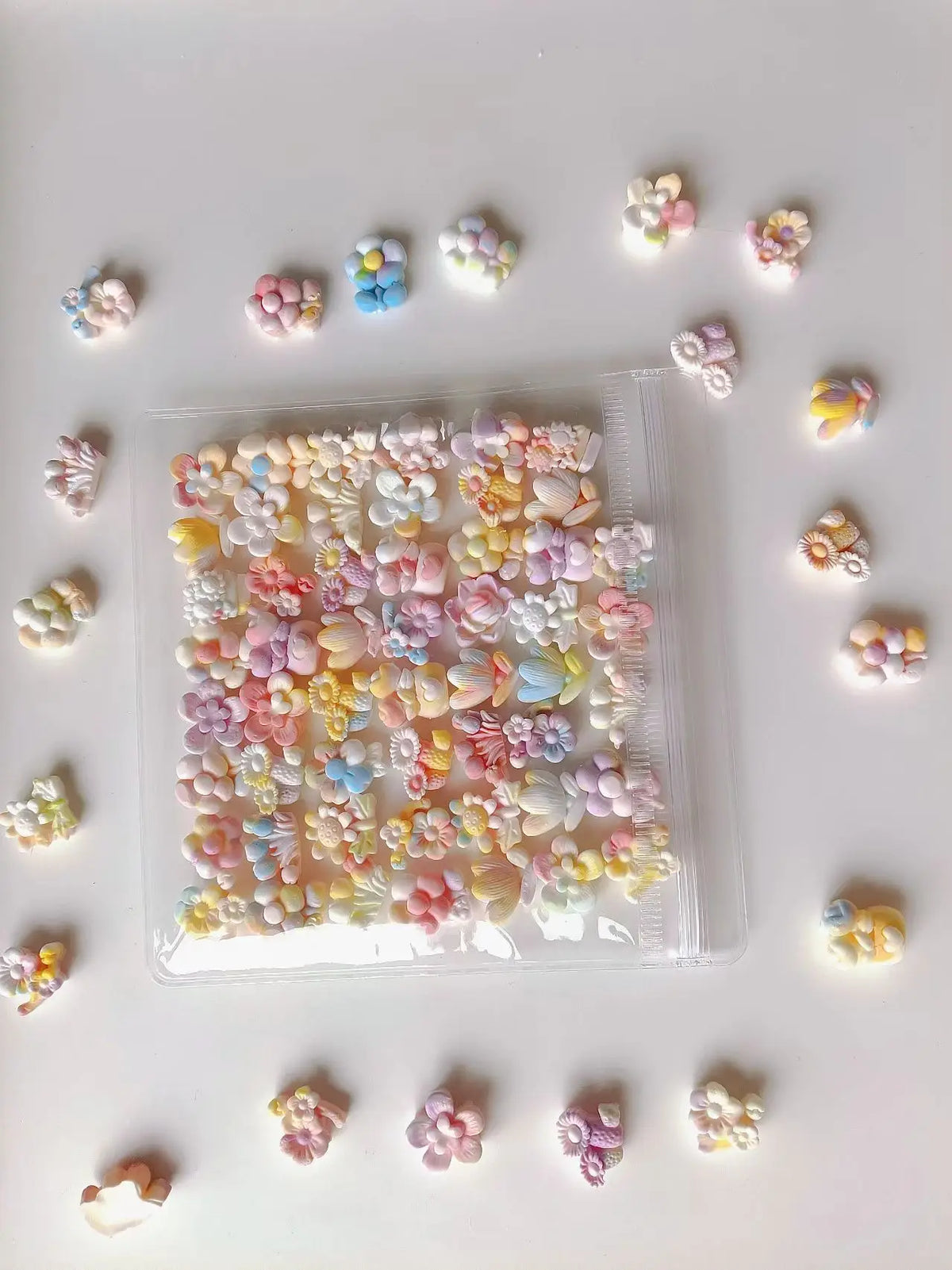 A clear plastic bag filled with numerous small, colorful floral-shaped squishy stress relief fidget toys scattered on a white