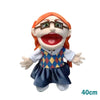 A realistic plush hand puppet with orange hair, glasses, and a wide open mouth, wearing a blue and yellow patterned outfit.