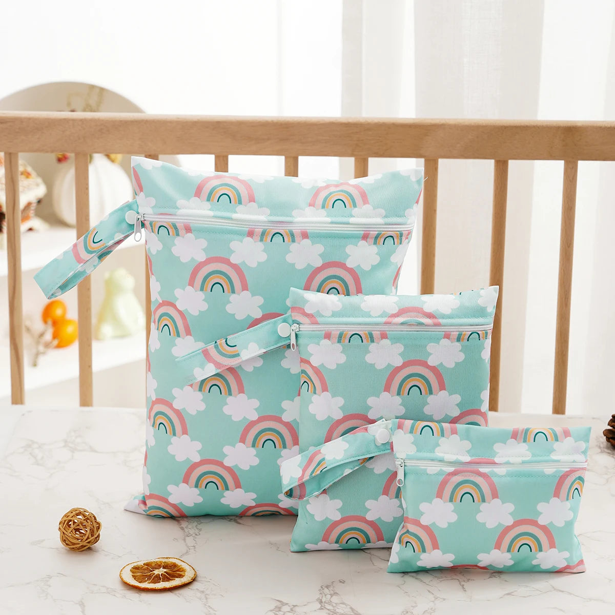 A set of three light blue waterproof bags with rainbow patterns for storing swimsuits, diapers, and travel items.